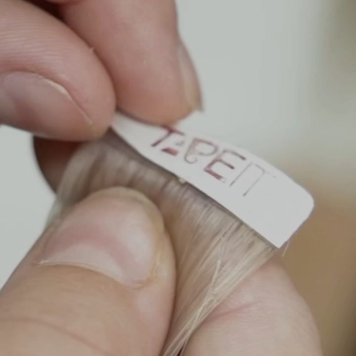 יד אוחזת מדבקת שיער בודדת עם סימון המותג