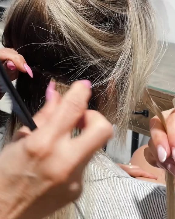 מעצב שיער מחלק מקטע שיער ומכין אותו לחיבור תוספת
